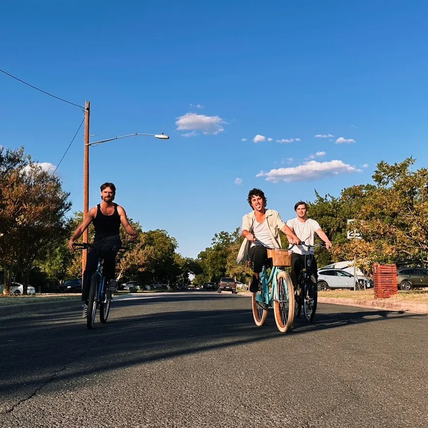 The three members of Scuff Up riding bikes down a street